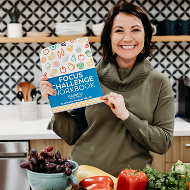 Steph Wagner holding Bariatric Nutrition Focus Challenge workbook in kitchen.