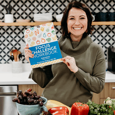 steph-wagner-bariatric-nutrition-specialist Steph Wagner holding Bariatric Nutrition Focus Challenge workbook in kitchen.